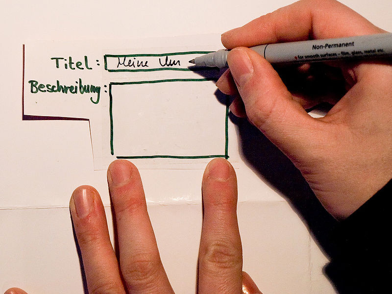 A participant writing in an input field on a paper prototype to simulate interaction with an unbuilt interface
