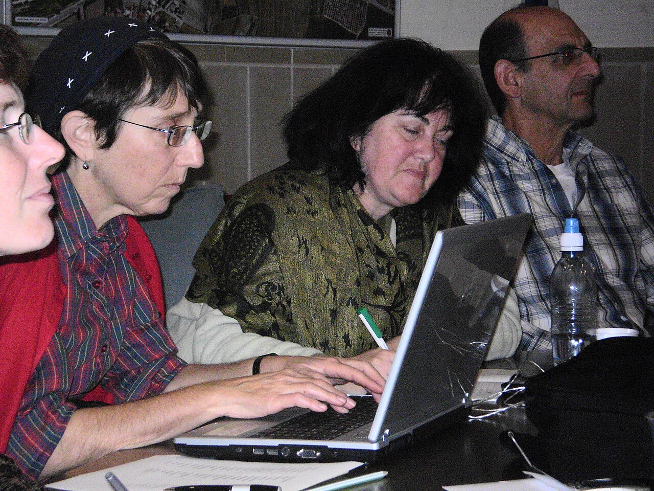 Participants in a real meeting taking notes with both computers and pen and paper